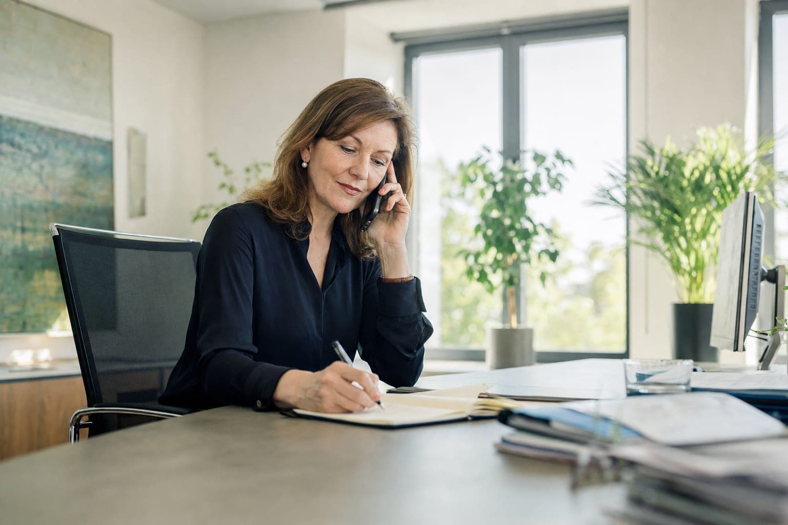 Recruiterin im Telefonat mit Notizblock am Schreibtisch